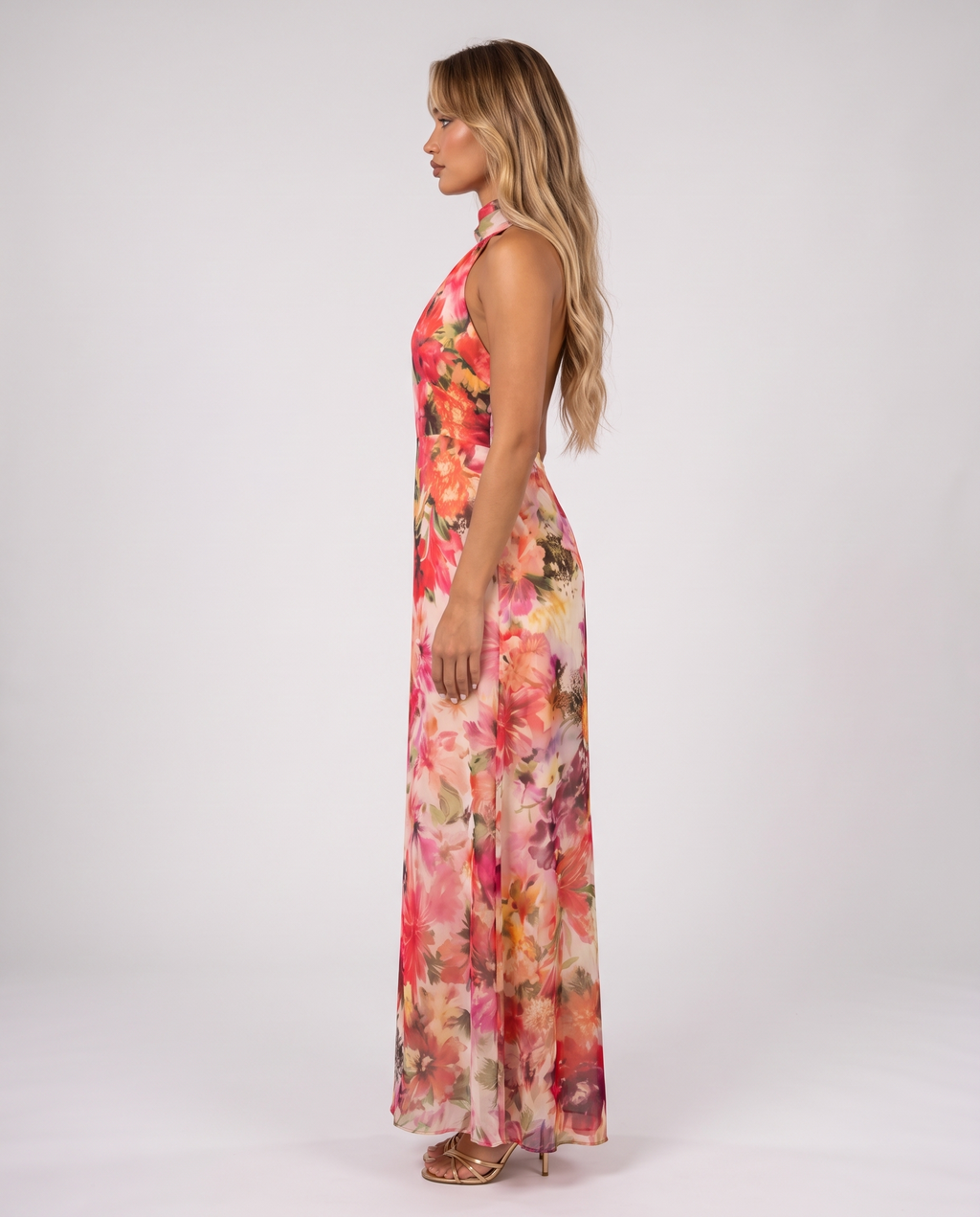 Women's coral pink floral halter neck maxi dress with a floaty A-line skirt, side view