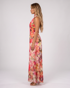 Women's coral pink floral halter neck maxi dress with a floaty A-line skirt, side view