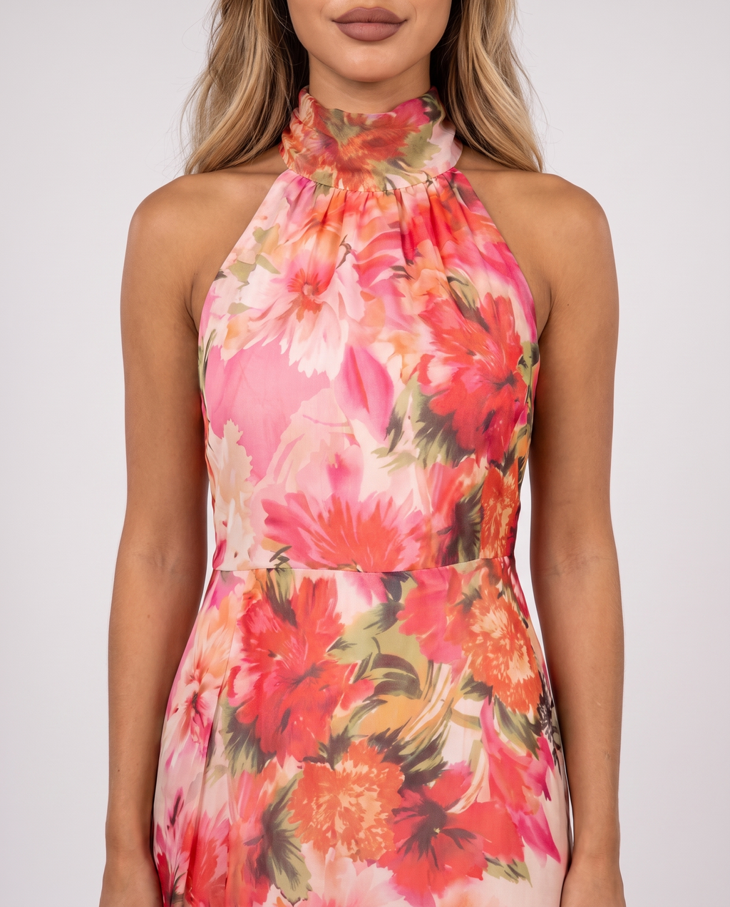 Women's coral pink floral halter neck maxi dress with a floaty A-line skirt, close-up of the gathered halter neckline