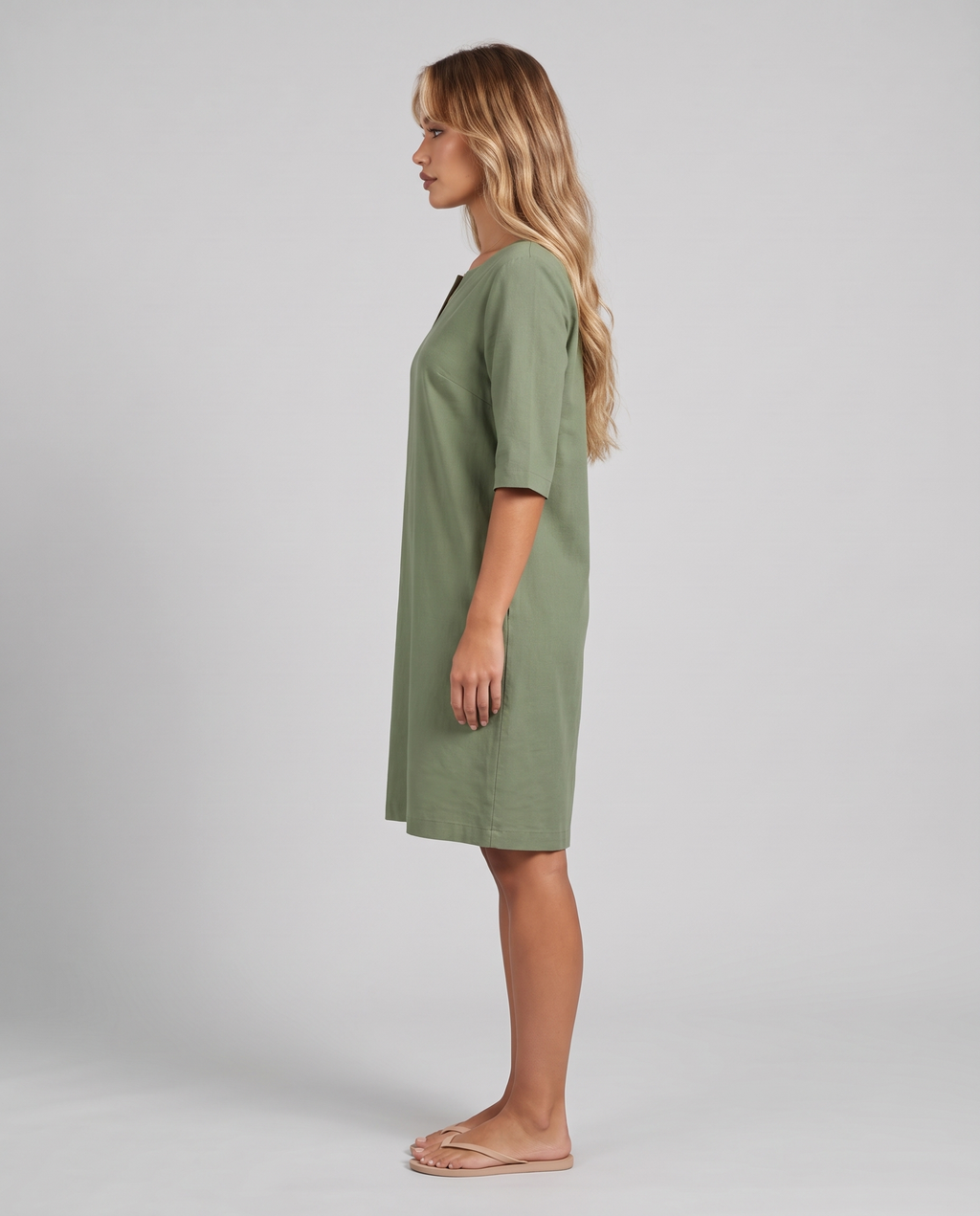 Women's sage green knee length shift dress with a notched neckline and elbow sleeves, side view