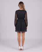Women's black sparkly mini dress with glitter stars, V-neck and long sleeves in sheer mesh, back view