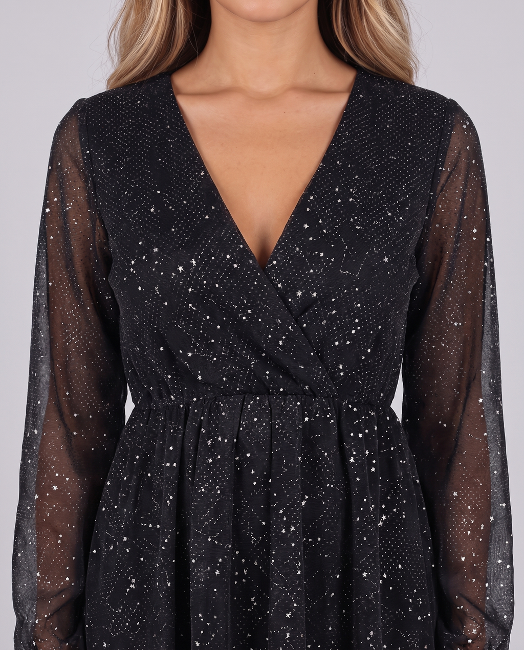 Women's black sparkly mini dress with glitter stars, V-neck and long sleeves in sheer mesh, close-up of the wrap bodice and glitter stars